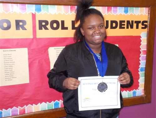 Sixth grade student wearing medal and holding reward for art 